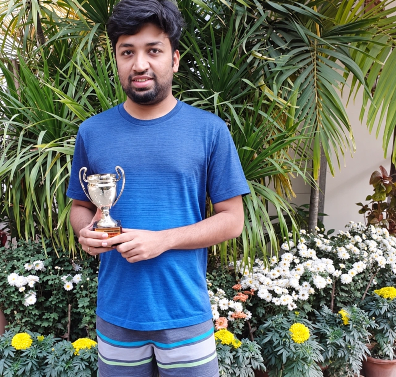 Enhanced archive photo of Sumesh holding his marathon trophy outdoors