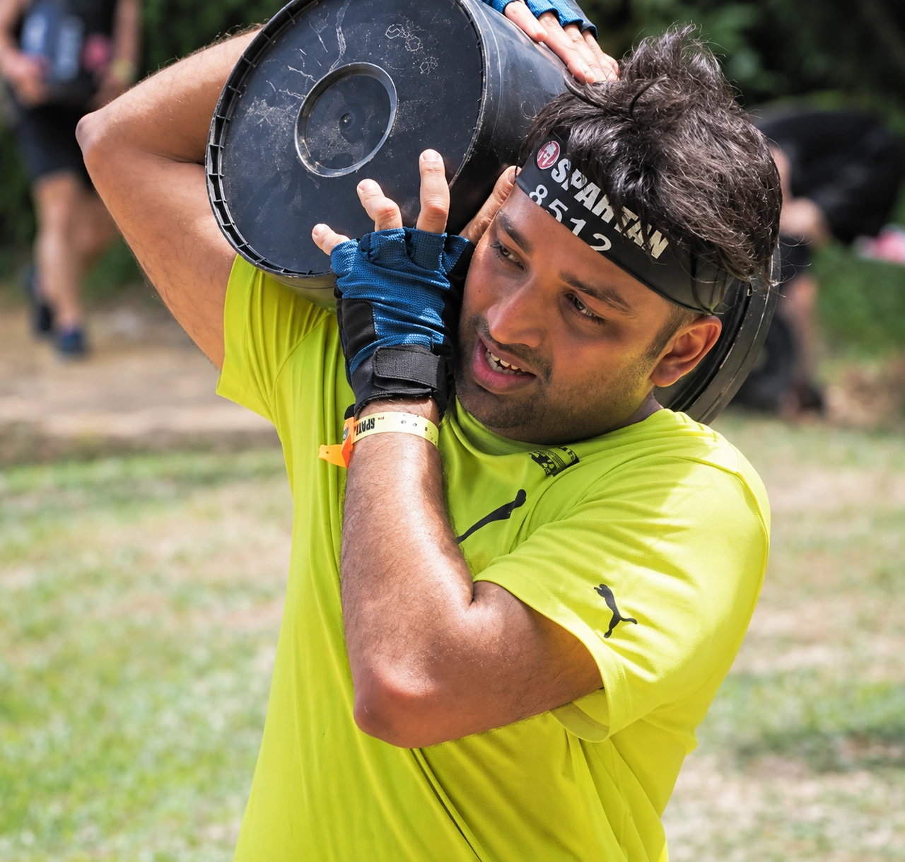Enhanced archive photo of Sumesh carrying a weight during a Spartan Race