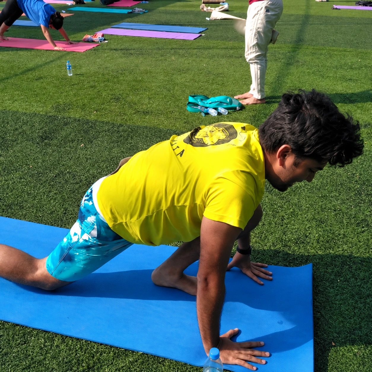 Enhanced archive photo of Sumesh practising yoga on a blue mat in an outdoor group session